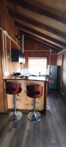 a kitchen with a desk and two bar stools at Cabañas Maullin in Maullín