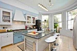 a kitchen with blue and white cabinets and a counter at Woodend Seaside Villa in Torquay