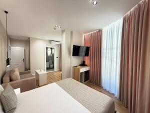 a bedroom with a bed and a couch and a television at Velour Boutique Hotel Durres in Durrës