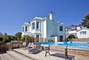 a house with a swimming pool in front of a house at Woodend Seaside Villa in Torquay