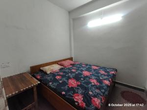 a small bedroom with a bed with a floral blanket at Gopal Sadan-2 in Vrindāvan
