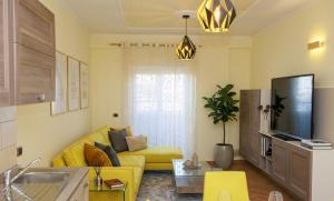 a living room with a yellow couch and a tv at Elena Seaview Apartment in Vlorë