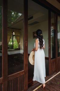 a woman in a white dress holding a hat at Kooncharaburi Resort - Koh Chang in Ko Chang