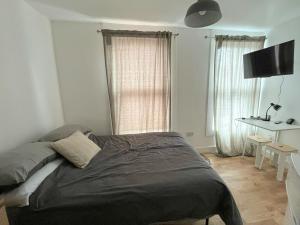 a bedroom with a bed and a desk and window at Casa Azul in Plumstead