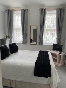 a bedroom with a large white bed with a mirror at Franklyn Guesthouse in Saint Helier Jersey