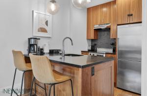 a kitchen with wooden cabinets and a counter with bar stools at 304 Newbury Street by Thatch in Boston