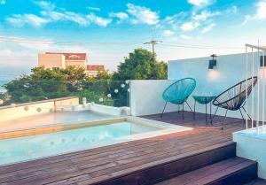 a hot tub sitting on a deck with two chairs at Jeju Semo, Byeol in Seogwipo