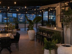 a restaurant with a bar with chairs and plants at DreamHaus Suites - Country Club Guadalajara in Guadalajara