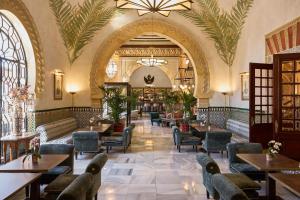 a restaurant with tables and chairs in a building at Alhambra Palace Hotel in Granada
