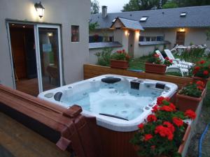 una bañera de hidromasaje en un balcón con una casa en Chambres d'hôtes Ferme de Gayri, en Vielle-Aure
