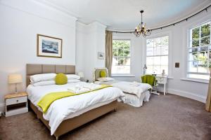 two beds in a bedroom with white walls and windows at Woodend Seaside Villa in Torquay +22 photos