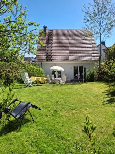 a house with a yard with chairs and an umbrella at Haus Else am Nationalpark Eifel in Schleiden