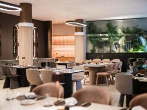 a restaurant with tables and chairs and a large screen at Diaco Boutique Hotel in Đakovo