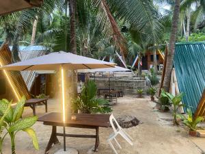 a wooden table with an umbrella and a chair at Sea Breeze Camp in Siquijor