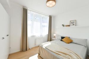 a white bedroom with a bed and a window at Apartmán Kolonáda in Poděbrady