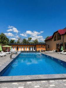 a large swimming pool with chairs and a building at HotelVizit in Solotvyno
