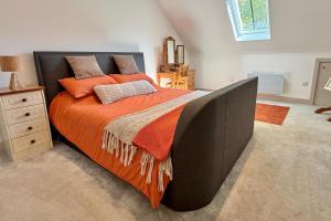 a bedroom with a large bed with an orange blanket at The Hayloft in Ringwood