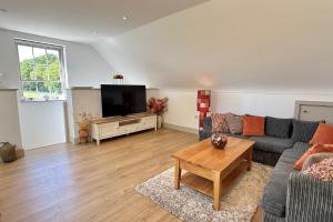 a living room with a couch and a tv at The Hayloft in Ringwood