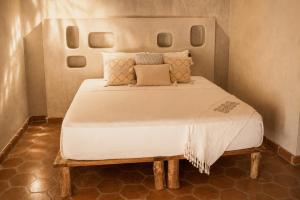 a bedroom with a large white bed with pillows at Casona Tunan in Santa María Mizata