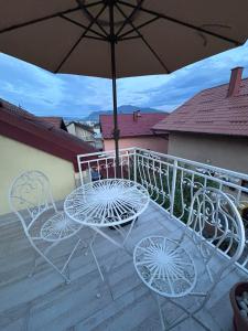 a table and chairs on a balcony with an umbrella at Duplex House - Private Home MUNA in Sarajevo