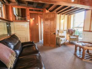 a living room with a leather couch and a table at Pearls Farm One in Macclesfield