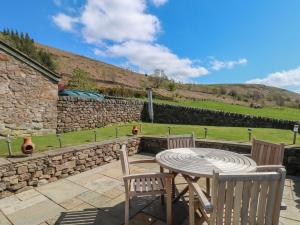 a patio with a table and chairs and a stone wall at Pearls Farm One in Macclesfield