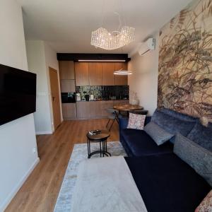 a living room with a blue couch and a kitchen at Park View Olszynki Park in Rzeszów +8 photos