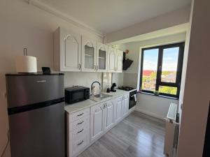 a kitchen with white cabinets and a stainless steel refrigerator at Anais Flower in Târgu Neamț