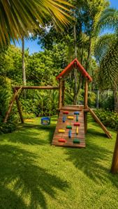 a playground with a wooden play set on the grass at Refúgio Casinha Branca in Duque de Caxias