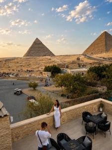 a man and a woman standing on a balcony looking at the pyramids at Cacillion Pyramids View in Cairo