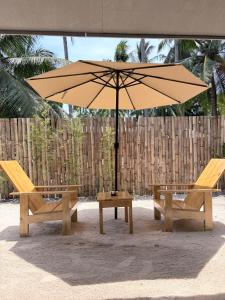 two benches and an umbrella on the beach at La Paula Hostel in San Juan