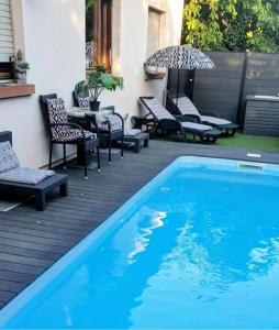 a swimming pool on a deck with chairs and an umbrella at Chambre cosy in Buhl