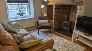 a living room with a leather couch and a fireplace at Troopers Cottage in Frome