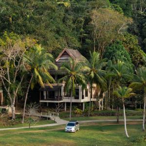 a house with palm trees and a car parked in front at Kooncharaburi Resort - Koh Chang in Ko Chang