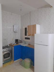 a kitchen with blue cabinets and a white refrigerator at Taguermess Tag 1 in Midoun