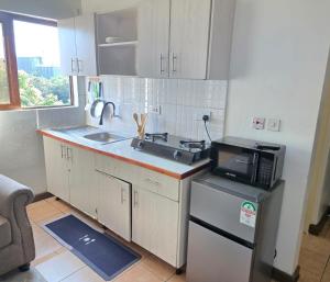 a small kitchen with a sink and a microwave at Emeli Suites in Nairobi