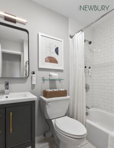 a bathroom with a toilet and a sink and a tub at 304 Newbury Street by Thatch in Boston +72 photos