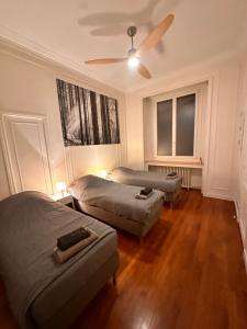 a bedroom with two beds and a ceiling fan at GRAND APPARTEMENT de 120 m2 à 5 minutes du Metro 7 lits in Les Lilas