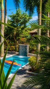 a swimming pool with a fountain and palm trees at Refúgio Casinha Branca in Duque de Caxias