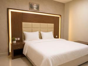 a bedroom with a large white bed with a wooden headboard at تراس للشقق المخدومة in Dammam