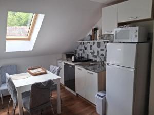 a small kitchen with a white refrigerator and a table at Dudov Hlad in Batina