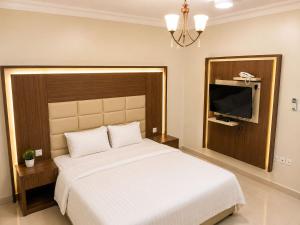 a bedroom with a large bed and a flat screen tv at تراس للشقق المخدومة in Dammam