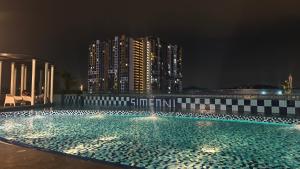 a swimming pool at night with buildings in the background at Eshue Designer Suites @ Simfoni Towers in Cheras