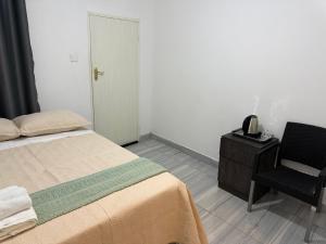 a bedroom with a bed and a chair and a phone at Shukuru Guest House in Harare