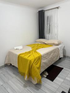a bedroom with two beds with a yellow blanket at Shukuru Guest House in Harare