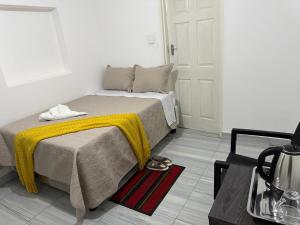 a bedroom with a bed with a yellow blanket on it at Shukuru Guest House in Harare