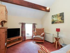a living room with a tv and a chair at Pearls Farm Two in Macclesfield
