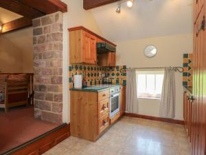 a kitchen with wooden cabinets and a stove top oven at Pearls Farm Two in Macclesfield