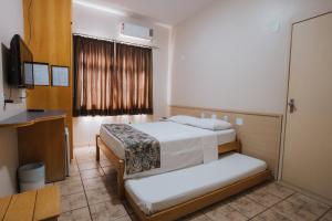 a hotel room with two beds and a television at Hotel Nacional Service - Fácil acesso a Região da 44 e Rodoviária in Goiânia