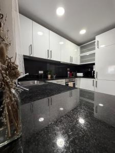 a kitchen with white cabinets and a black counter top at A Janela do Cantinho in Reguengos de Monsaraz